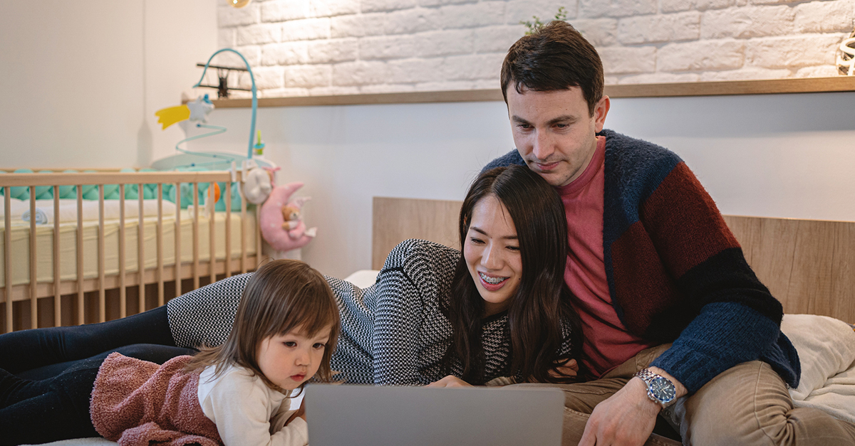 A young family watches cartoons with on their laptop