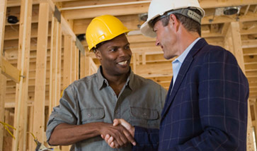 two men in hard hats shaking hands